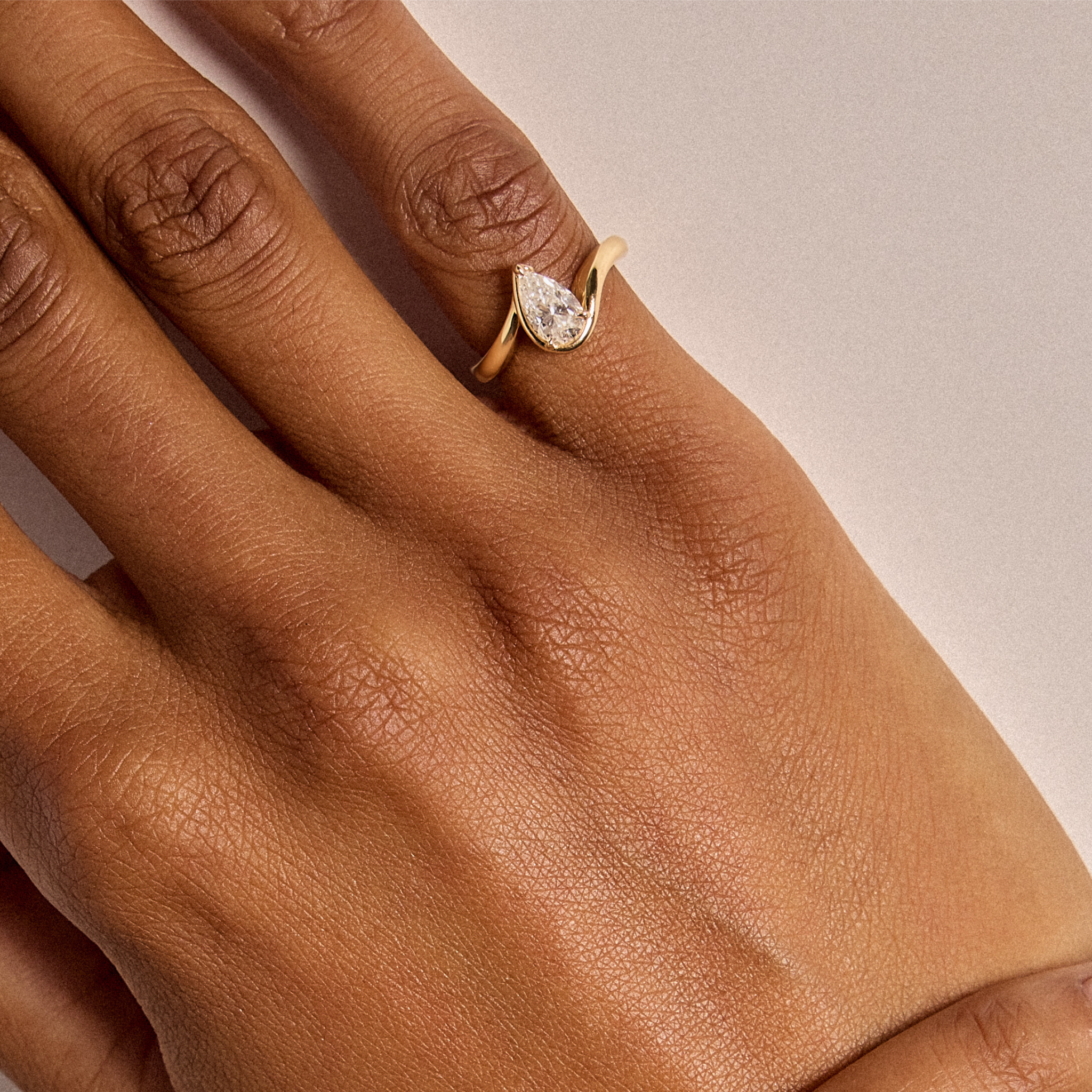 Hand model wearing BB Talia White Diamond in 14k yellow gold on right hand pinky in front of a white wall.