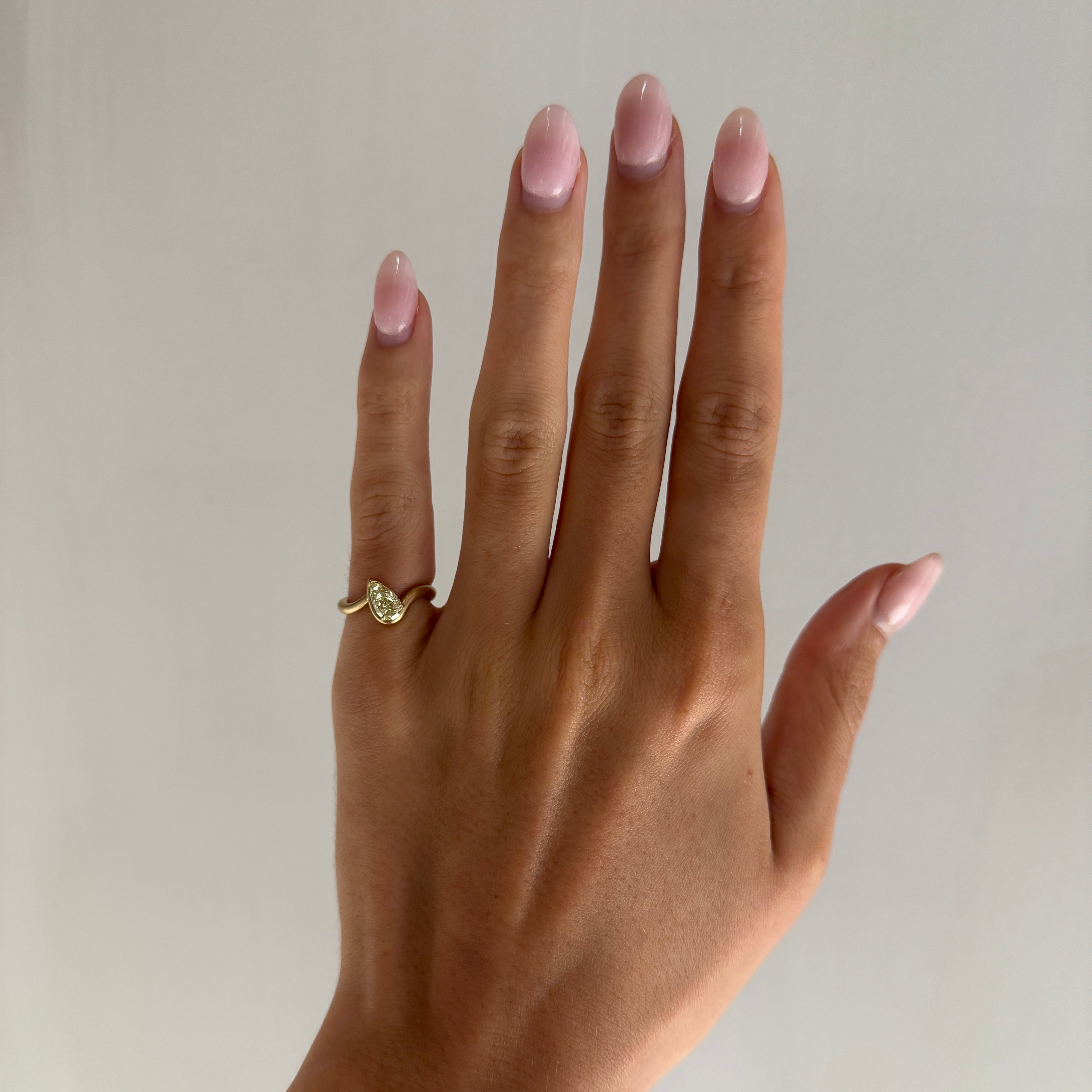 Hand model wearing BB Talia Yellow diamond in 14k yellow gold on left hand pinky in front of a white wall.