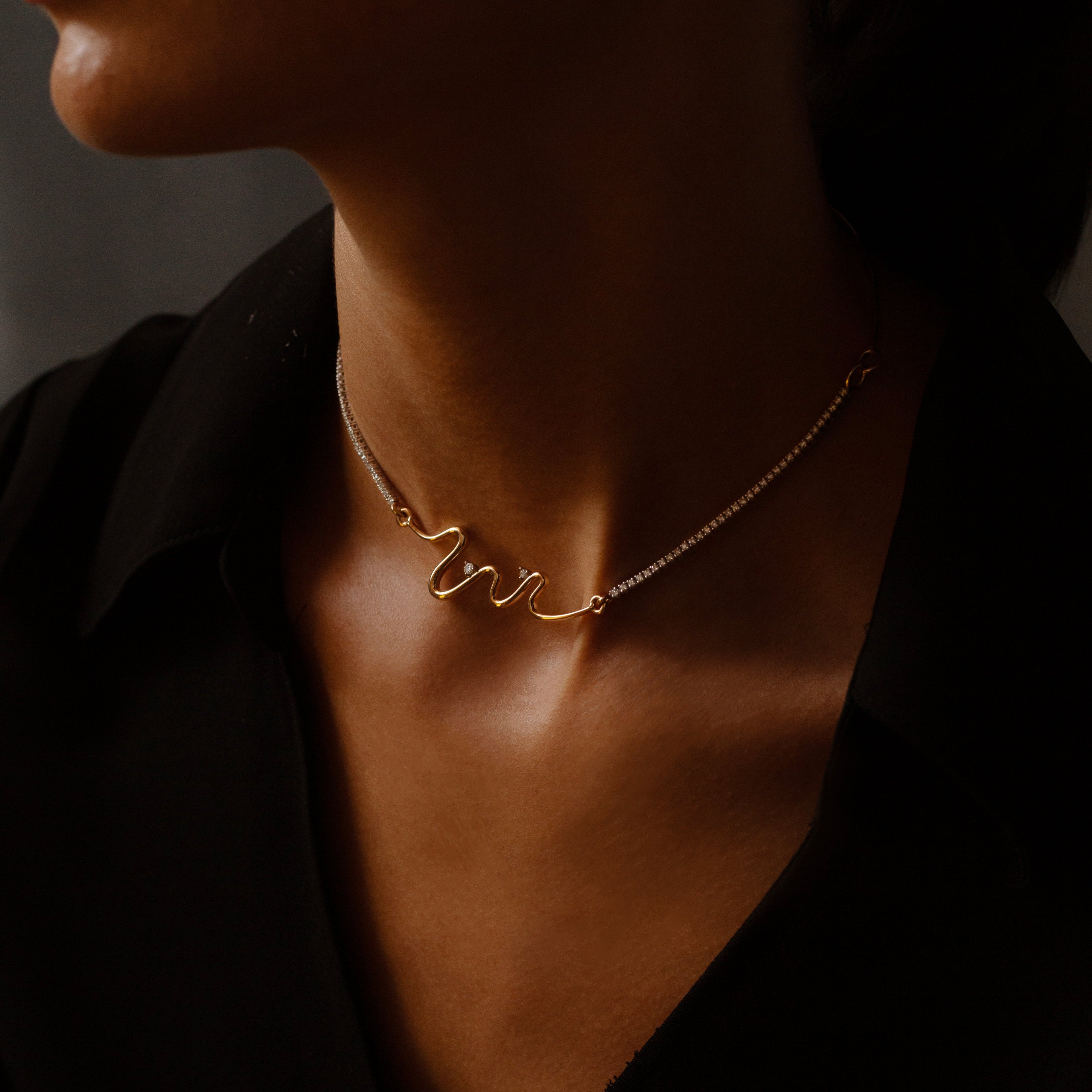 Close-up of a person wearing an Estela Swiggle Necklace 14kt yellow gold necklace against a dark background