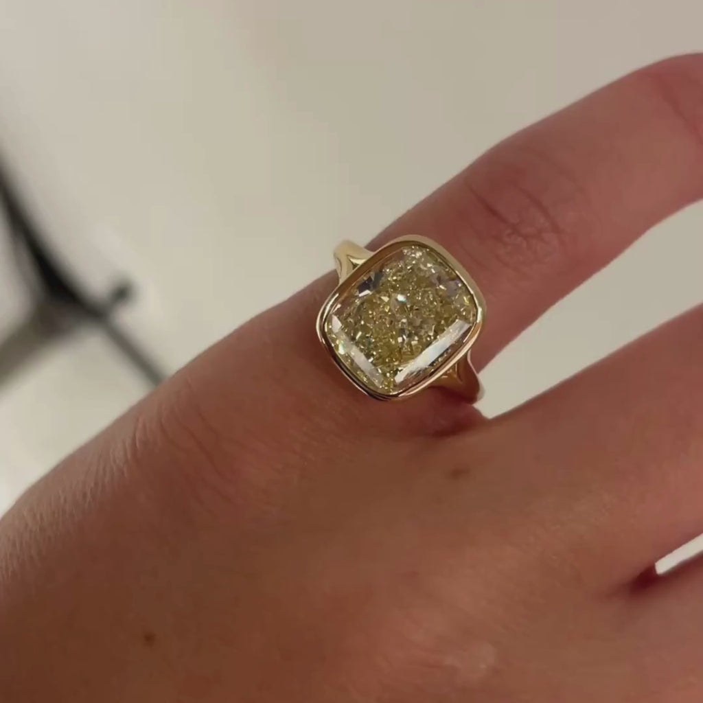 Bespoke Yellow Cushion Diamond, Bezel Set with split shank band, 18kt Yellow gold in a high finish. Closeup on hand. 